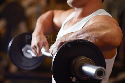 Buy stock photo A young man lifting a dumbbell at the gym