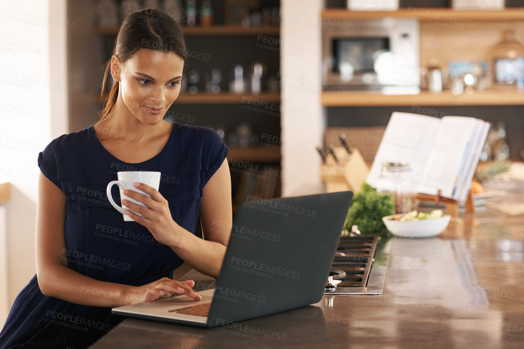 Buy stock photo Shot of an attractive young woman using her laptop while enjoying a cup of coffee