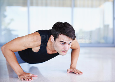 Buy stock photo A cropped shot of a focused young man doing strength exercises at home