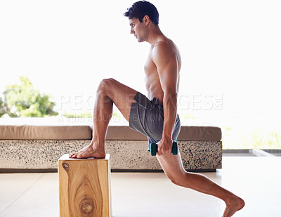 Buy stock photo A muscular young man doing strength exercises with dumbbells at home