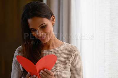 Buy stock photo Shot of an attractive young woman reading a valentine's day card at home