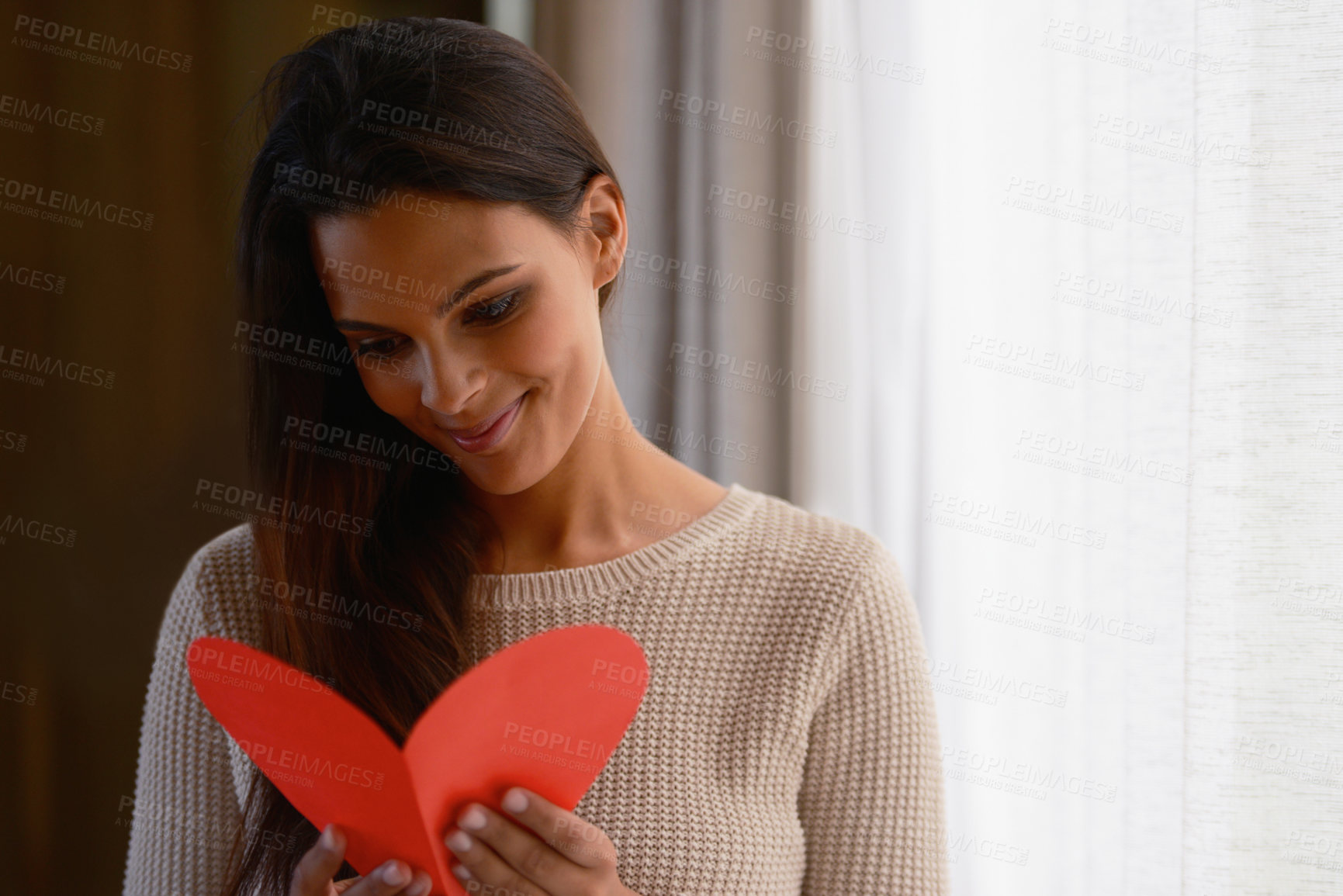 Buy stock photo Shot of an attractive young woman reading a valentine's day card at home