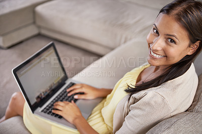 Buy stock photo Portrait of an attractive young woman using her laptop while sitting on the couch