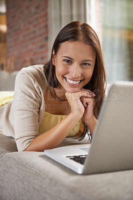 Buy stock photo Portrait of an attractive young woman lying on a sofa with a laptop