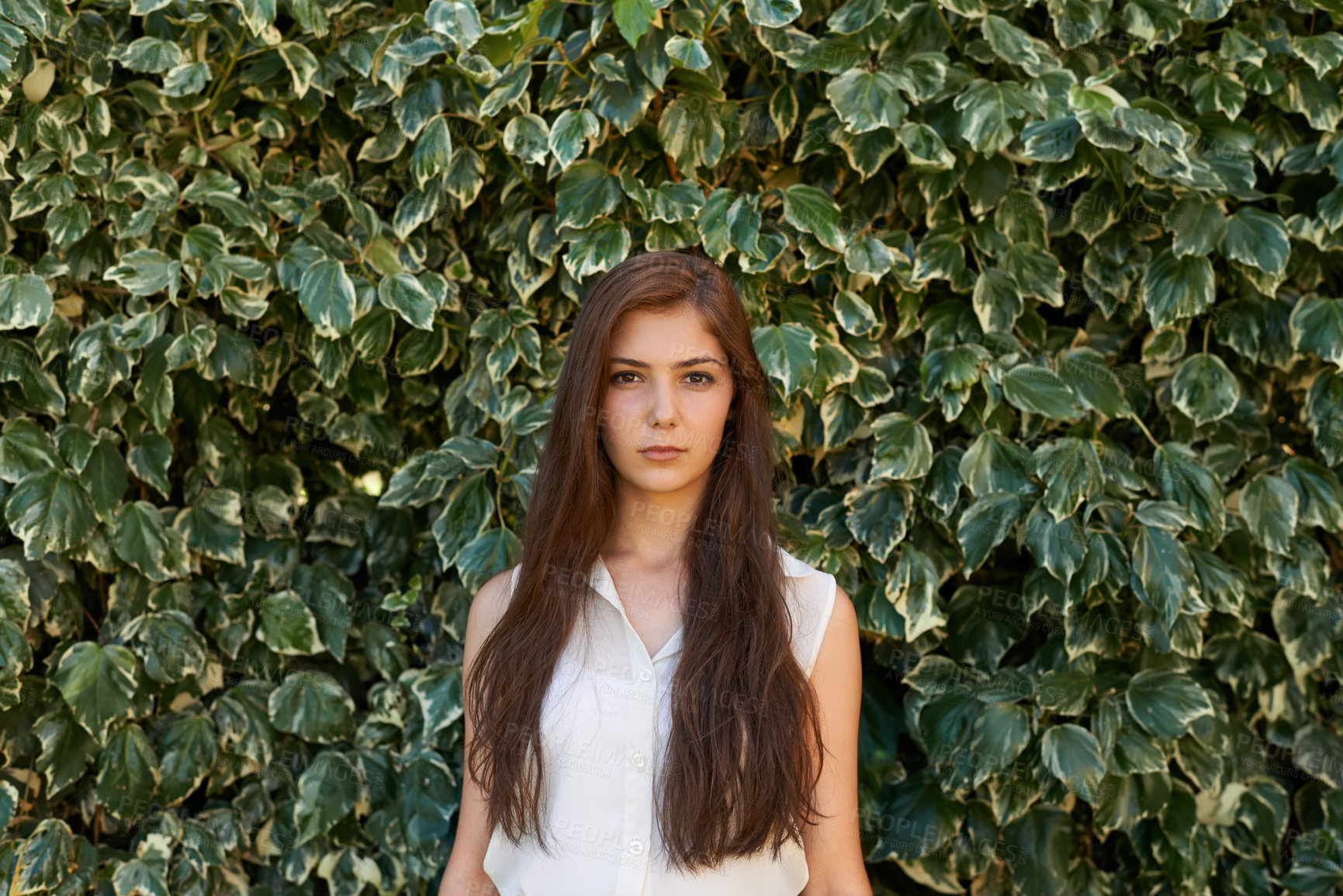 Buy stock photo Woman, portrait and serious by hedge outdoor with travel, summer holiday or casual fashion in park. Girl, face and confidence at leaf fence in garden for relax, wellness or trendy outfit in Amsterdam