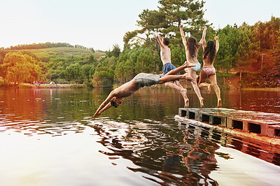 Buy stock photo Lake, pier and friends jump in water on vacation in summer or holiday together in nature for adventure. Group, energy and enjoy river on deck with freedom or people swimming outdoor in dam for fun