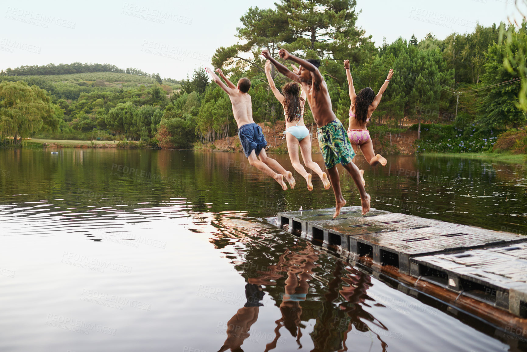 Buy stock photo Lake, pier and friends jump in water on vacation in summer or holiday together in nature with adventure. Excited, group and enjoy river on deck with freedom or people swimming outdoor in dam for fun