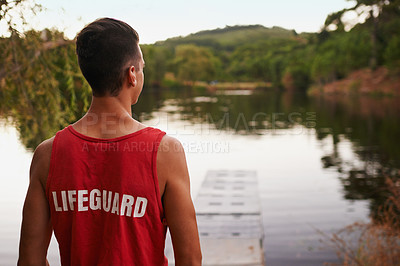 Buy stock photo Back view, lifesaver and landscape outdoor at lake, river and working for safety, security and health of people swimming. Young man, male person and youth in nature, forest and environment with water
