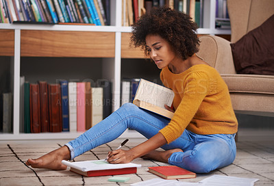 Buy stock photo Cropped shot of an attractive young woman sitting on the floor while studying
