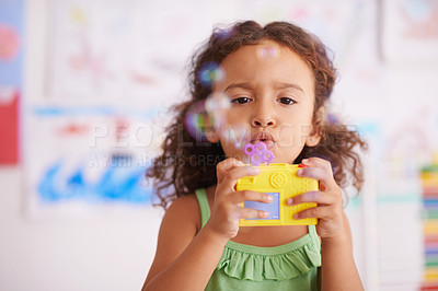 Buy stock photo Preschool, toy and girl playing with bubbles for growth and development of child with game. Kindergarten, soap and wand with cute kid for fun in classroom with drawings by youth in background 