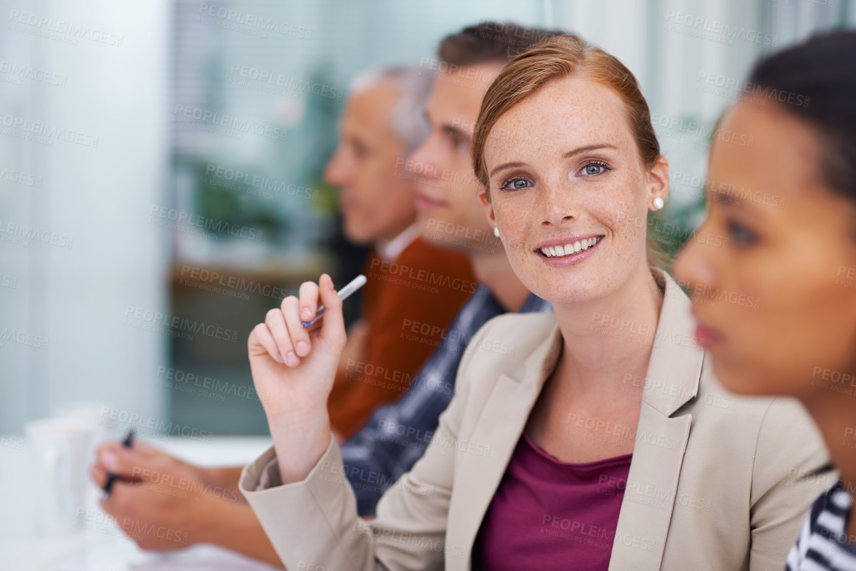 Buy stock photo Shot of a businesswoman smiling at the camera during a meeting with her colleagues