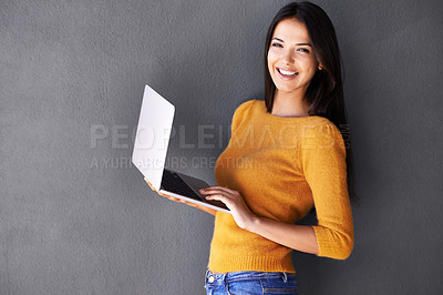 Buy stock photo Portrait of a beautiful young woman using a laptop against a gray background