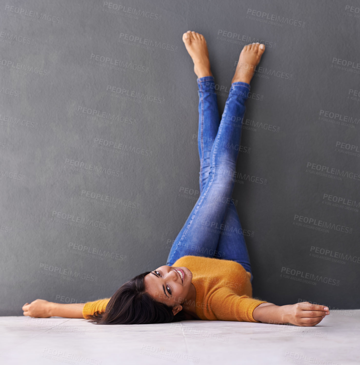 Buy stock photo Portrait, woman and smile to relax on floor with a dark wall background in casual style. Leisure, rest and face of female person with rest and fashion upside down with her feet on a studio backdrop