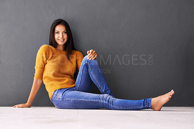 Buy stock photo Portrait, woman and relax or style on floor with casual outfit for fashion or comfort, leisure and wellness with smile. Female person, isolated with grey background or wall for clothing with mockup