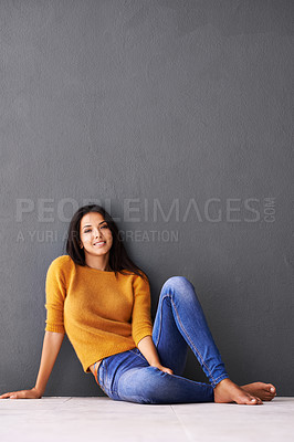 Buy stock photo Portrait, girl and relax or chill on floor with casual outfit for fashion or comfort, leisure and wellness with smile. Female person, isolated with grey background or wall for clothing with mockup.