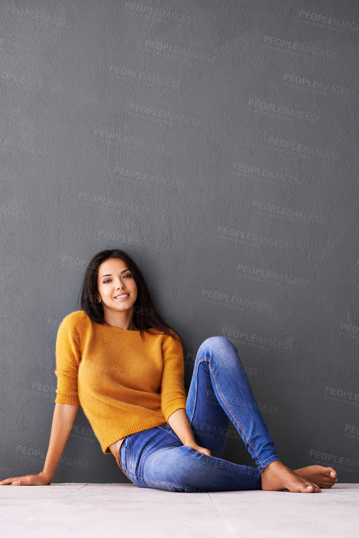 Buy stock photo Portrait, girl and relax or chill on floor with casual outfit for fashion or comfort, leisure and wellness with smile. Female person, isolated with grey background or wall for clothing with mockup.