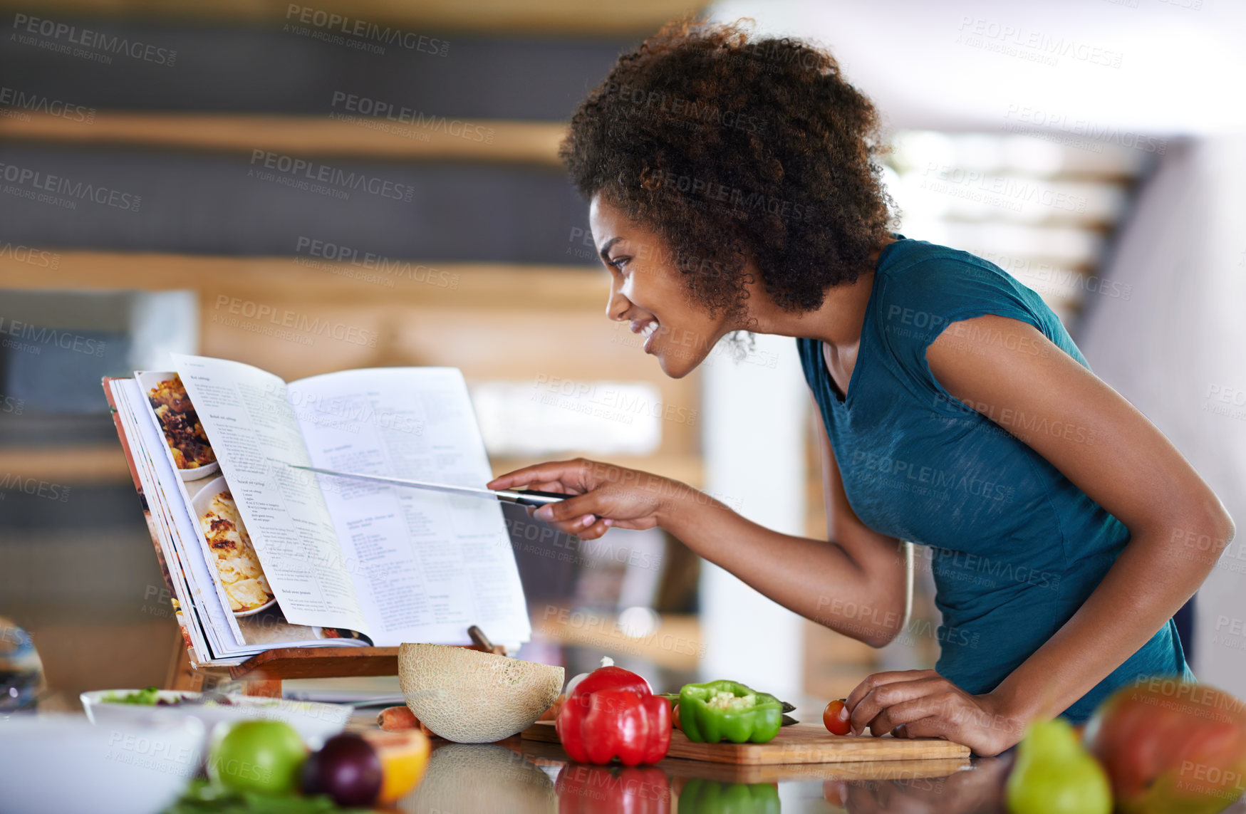 Buy stock photo A young woman cooking from a recipe book