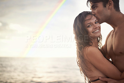 Buy stock photo Couple, hug and kiss by ocean, nature and rainbow with travel for happy people on vacation. Romantic adventure together, relax outdoor and bonding for love, care and trust in healthy relationship
