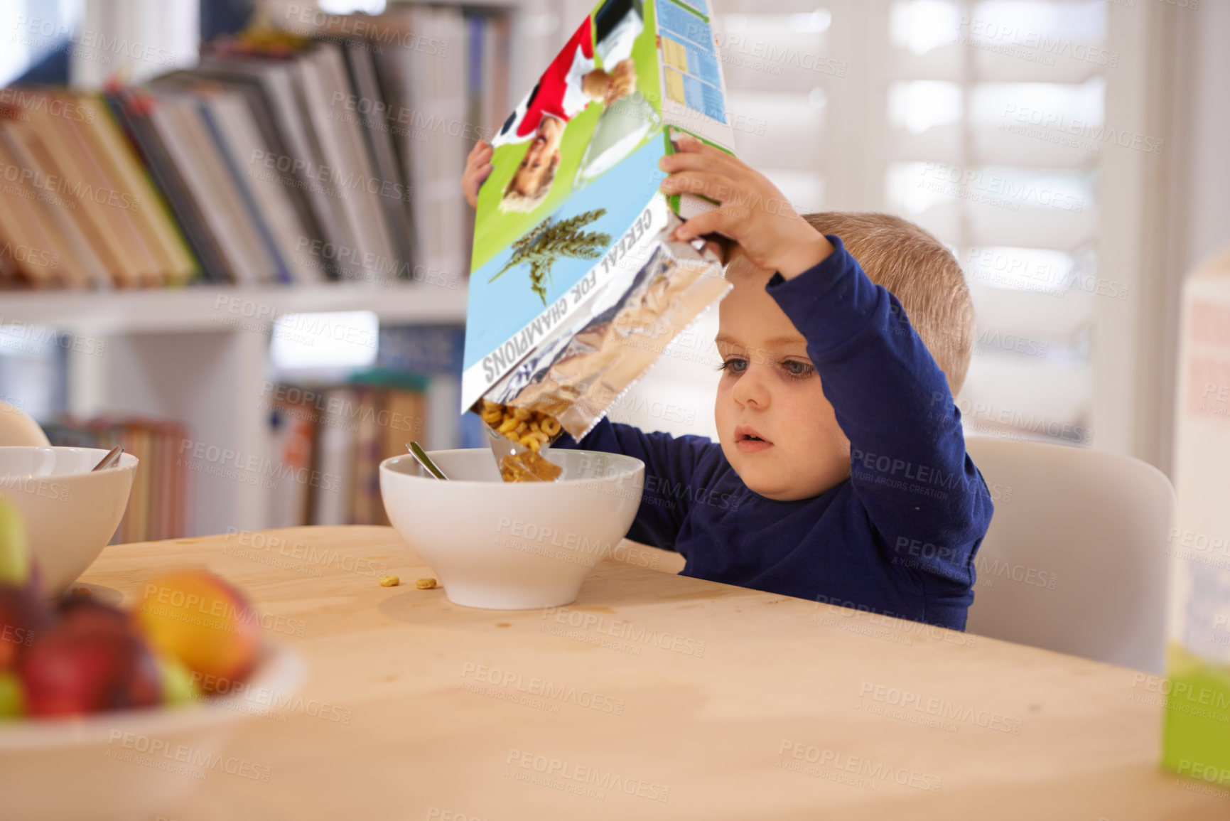 Buy stock photo Cropped shot of a young boy pouring his breakfast into a bowl at home