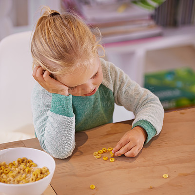 Buy stock photo Shot of a little girl looking sad while eating breakfast at home