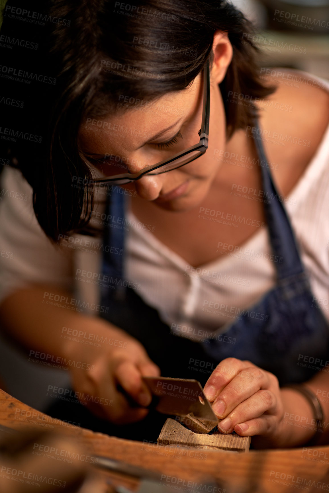 Buy stock photo Carving, wood and artist in workshop with tools for creative project or sculpture on table at night. Artisan, carpenter and woman with talent for creativity in dark studio in process of woodworking