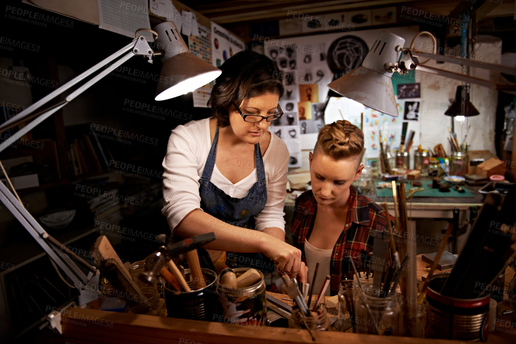 Buy stock photo Women, craft and tools in workbench for creative design, wood sculpture or handmade project at night. Artist, collaboration and manufacturing in studio with teamwork, assistance and workshop skills