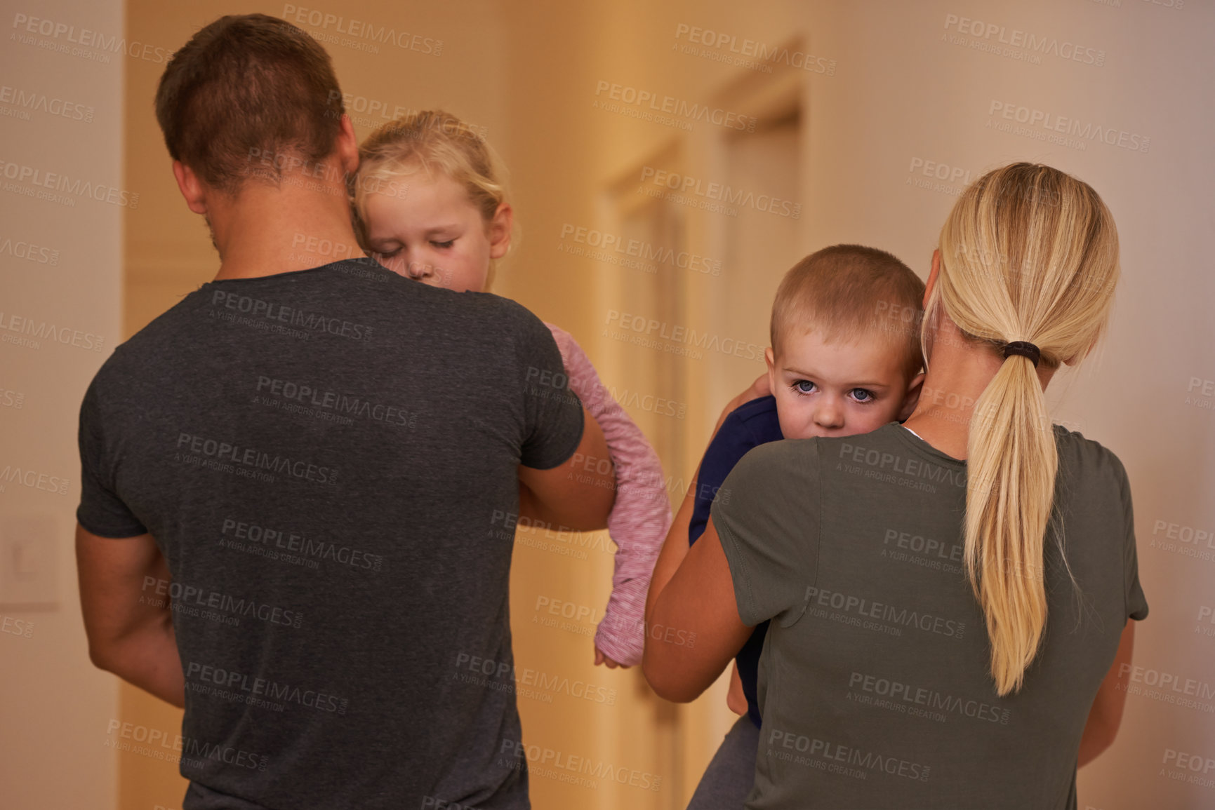 Buy stock photo Shot of young parents carrying their sleepy children to bed