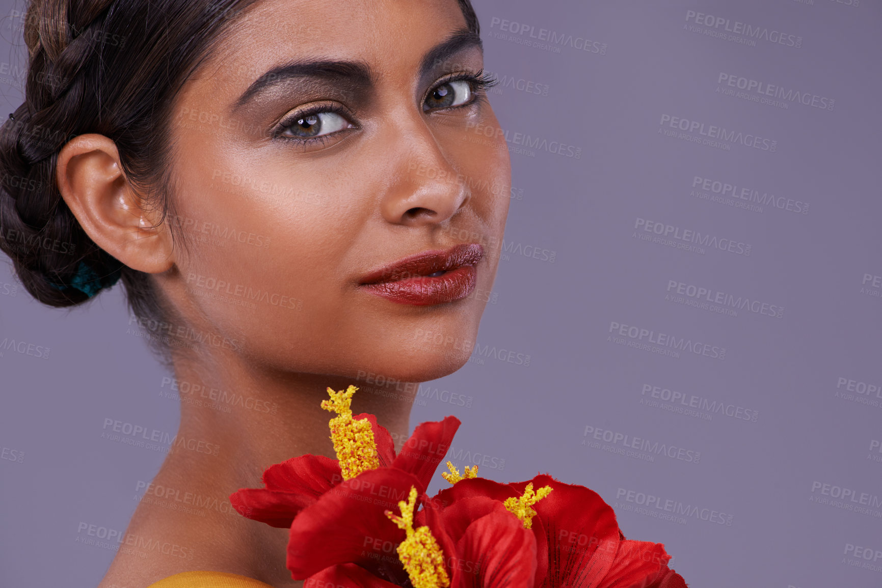 Buy stock photo Portrait, beauty and woman with flowers for skincare, makeup or mockup isolated on a purple studio background in India. Face, model and cosmetics with bouquet for natural skin with organic hibiscus