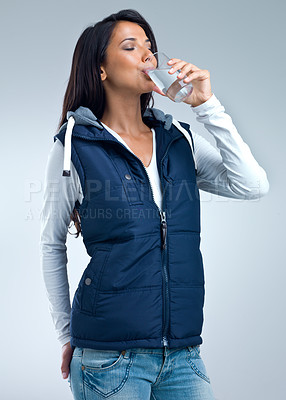 Buy stock photo Woman, drinking water for health and hydration in studio, nutrition and wellness with thirst on grey background. Liquid, aqua and mineral with h2o in glass, fresh and clean for refreshment and detox