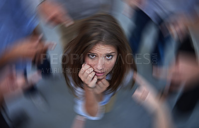 Buy stock photo Conceptual shot of an anxious young woman in the middle of a circle of accusing coworkers