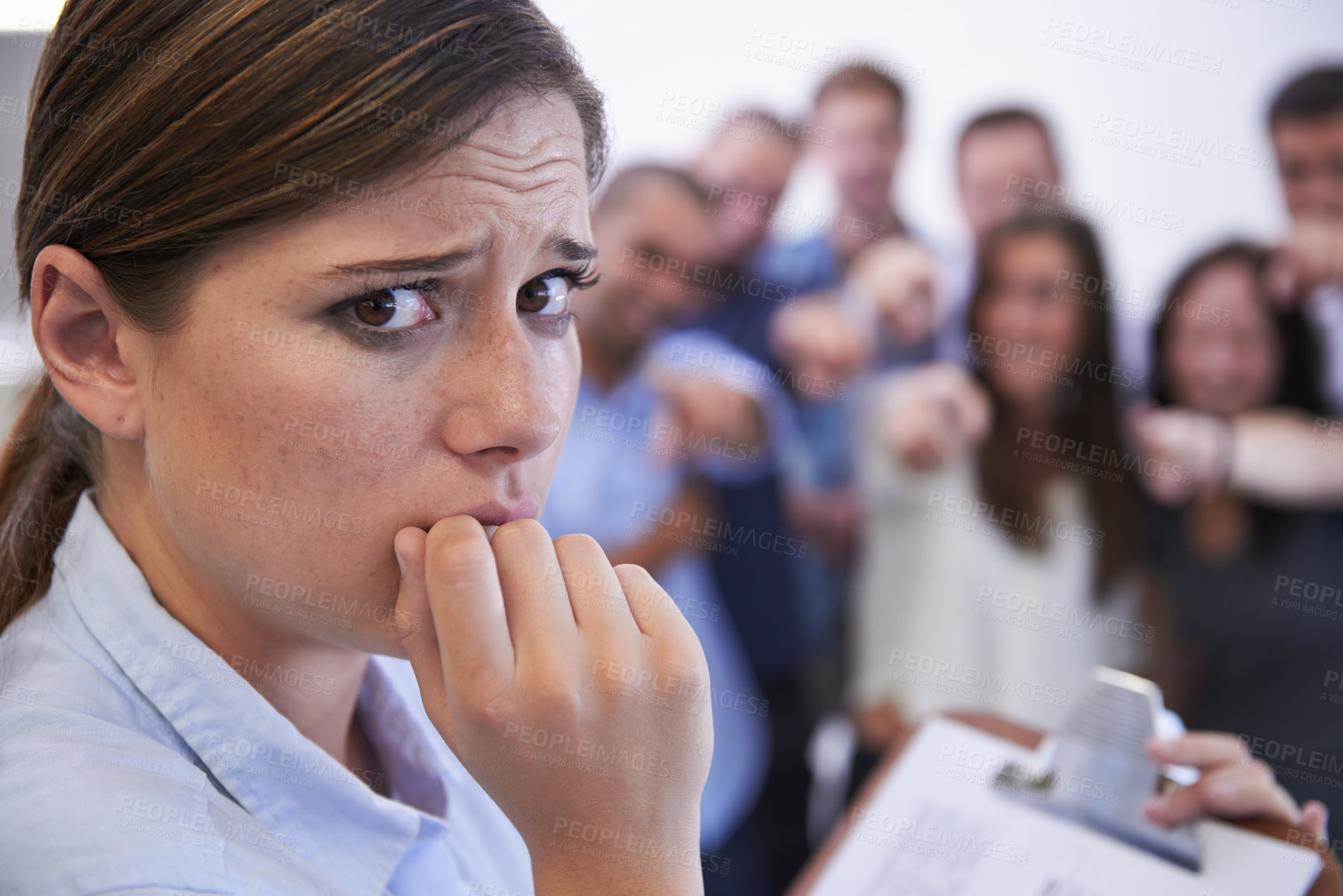 Buy stock photo Closeup of an anxious young woman facing the accusatory fingers of her coworkers