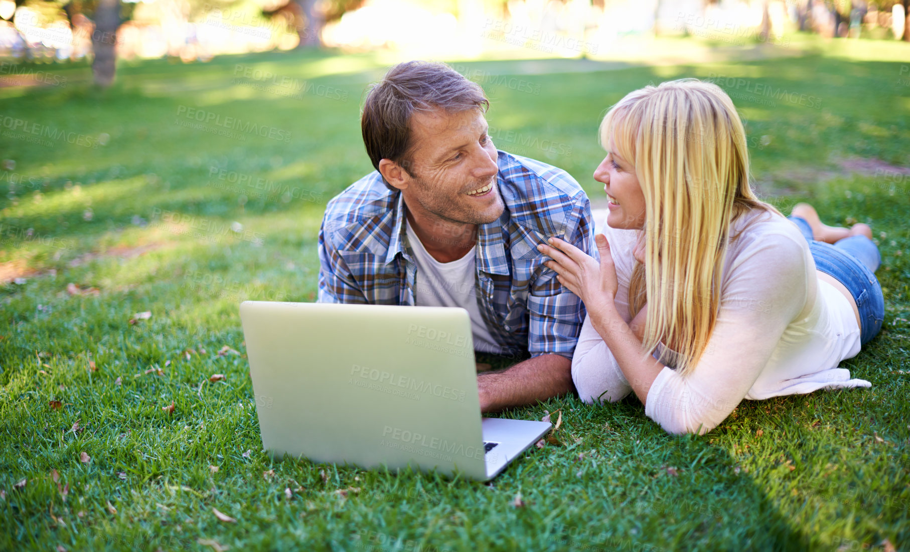 Buy stock photo Cropped shot of an attractive couple using a laptop outdoors