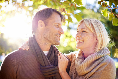 Buy stock photo Man, woman and smile in park environment for love anniversary in autumn weather with warm clothes, scarf or date. Happy couple, happiness and nature with trees or sunshine travel, relax or holiday