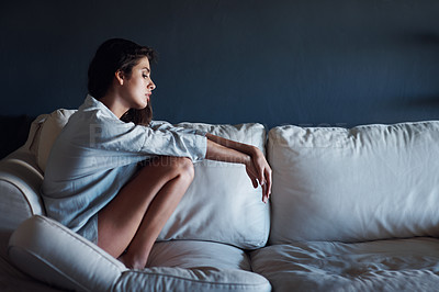 Buy stock photo Depression, sad and woman relaxing on sofa in living room for loneliness at modern house. Mental health, upset and unhappy young female person sitting, resting and thinking on couch at apartment.