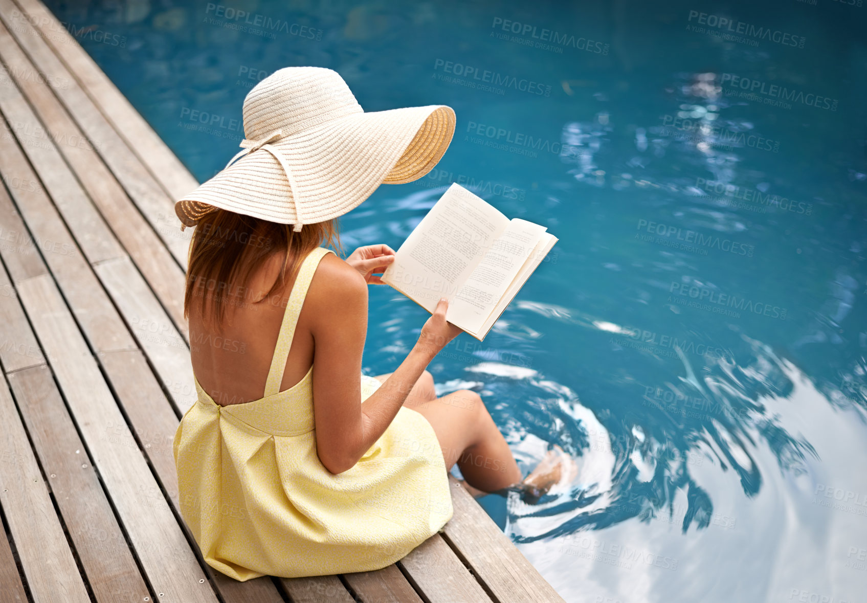 Buy stock photo young woman relaxing at the pool with a book