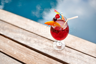 Buy stock photo A fruity cocktail on a wooden deck next to an outdoor pool
