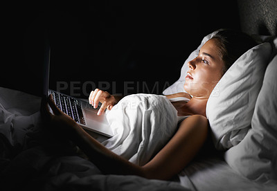 Buy stock photo A pretty brunette browsing on her laptop while lying in bed
