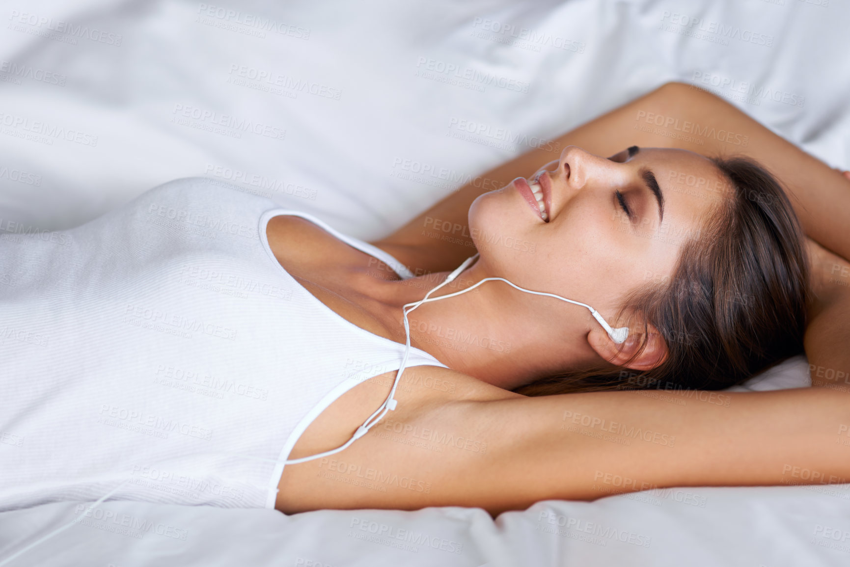 Buy stock photo Portrait of a beautiful young woman listening to music while lying on her bed