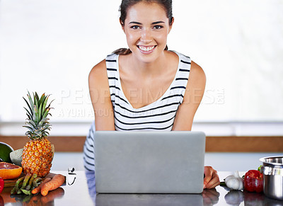 Buy stock photo A beautiful young woman browsing the internet for recipes in her kiitchen