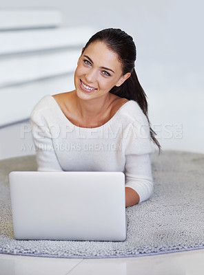 Buy stock photo A beautiful young woman lying on her floor at home and using a laptop