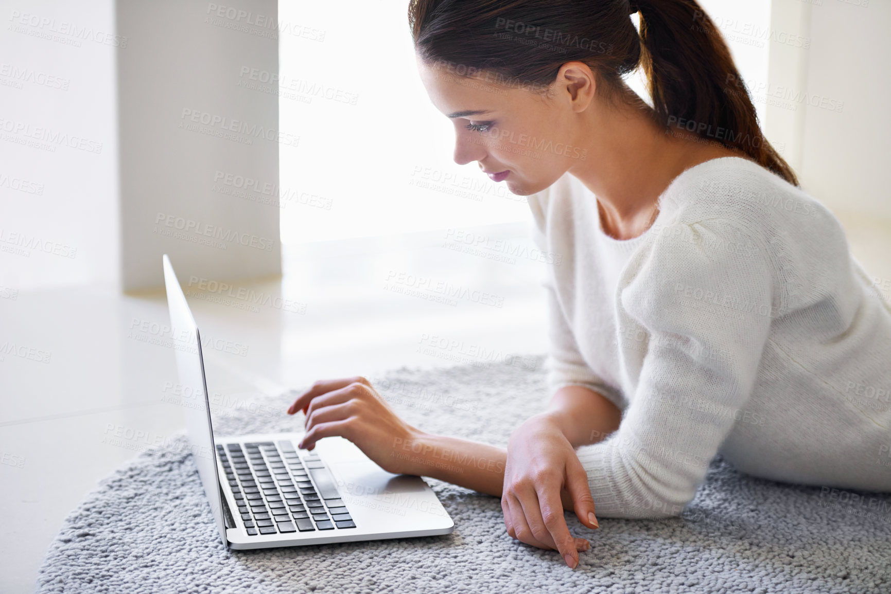Buy stock photo A beautiful young woman lying on her floor at home and using a laptop
