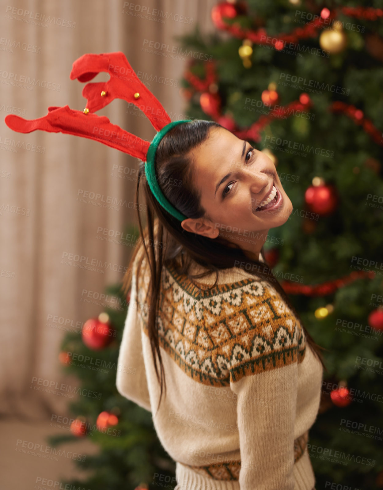 Buy stock photo Portrait, happy and woman in home for Christmas, party or holiday in apartment in Spain. Xmas, face and smile of female person in antlers for festive celebration, funny and laughing by tree in house