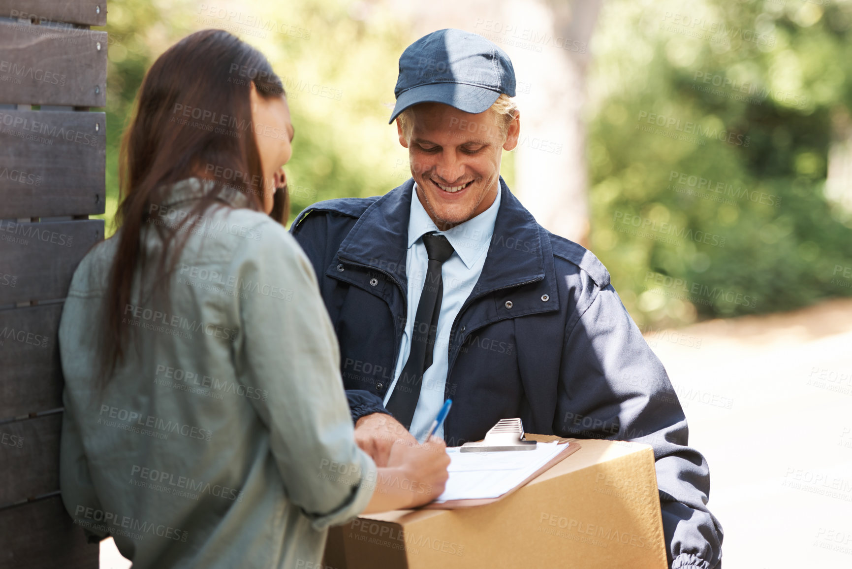 Buy stock photo Shot of a courier delivering a package to a young woman