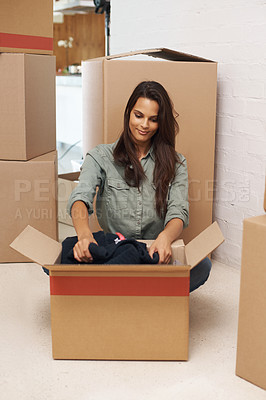 Buy stock photo A beautiful young woman sitting on the floor in her new house and unpacking boxes