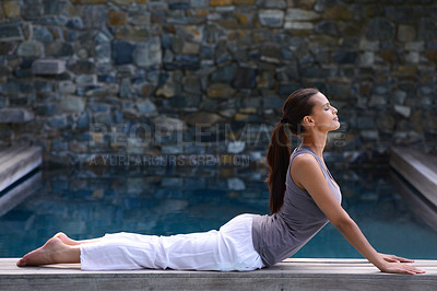 Buy stock photo A beautiful young woman doing yoga beside a pool