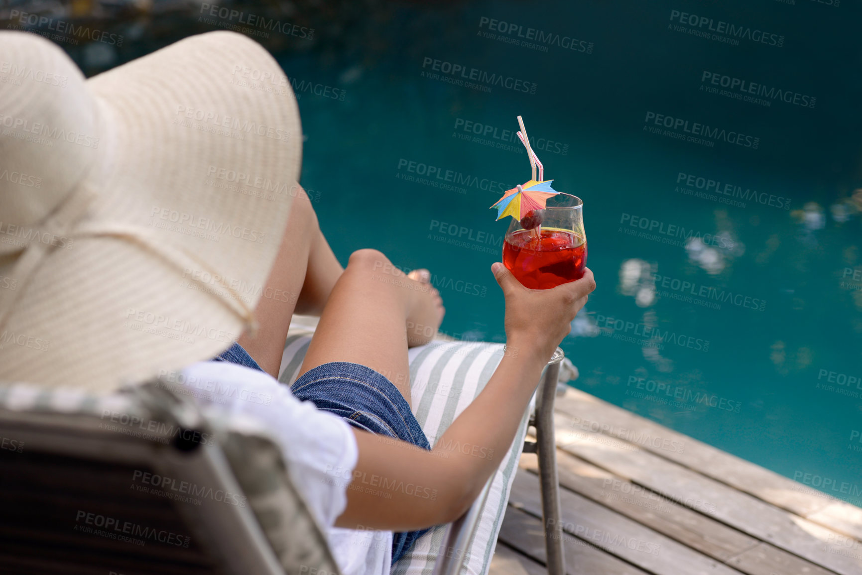 Buy stock photo A young woman sitting by the poolside with a cocktail in her hand