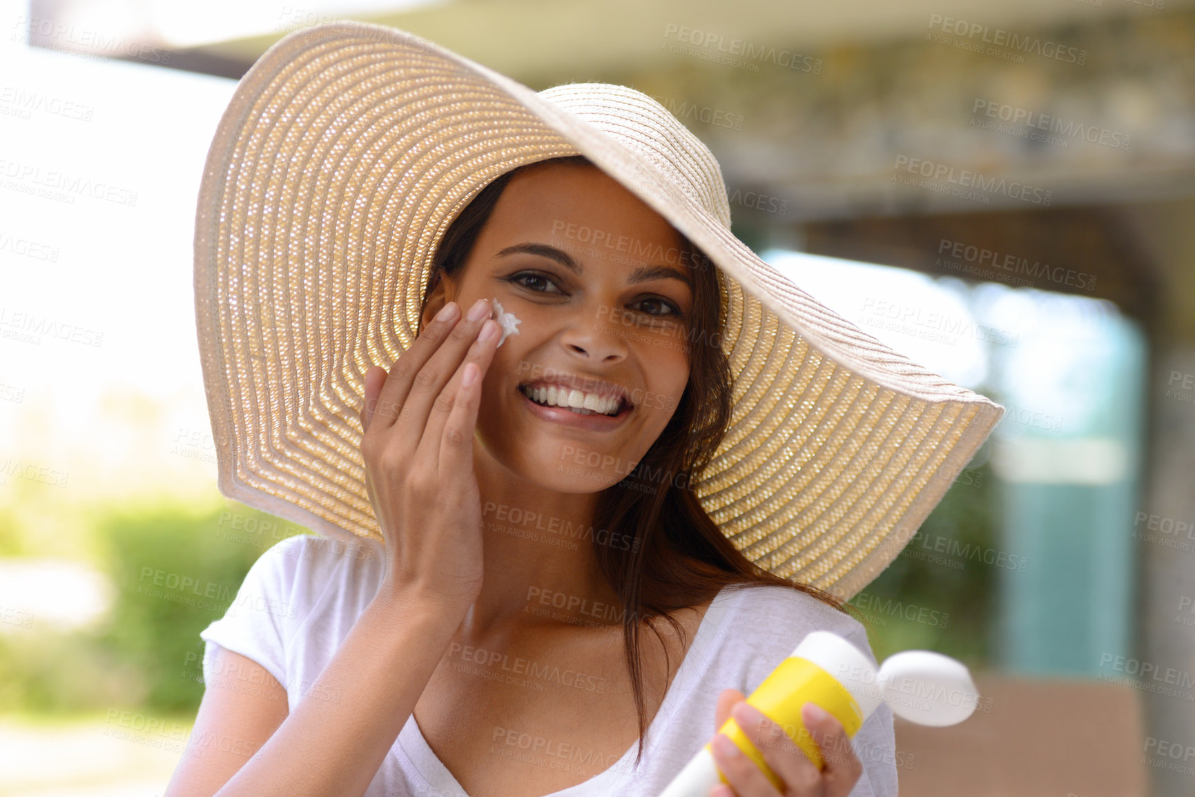Buy stock photo An attractive young woman applying sunscreen to her face