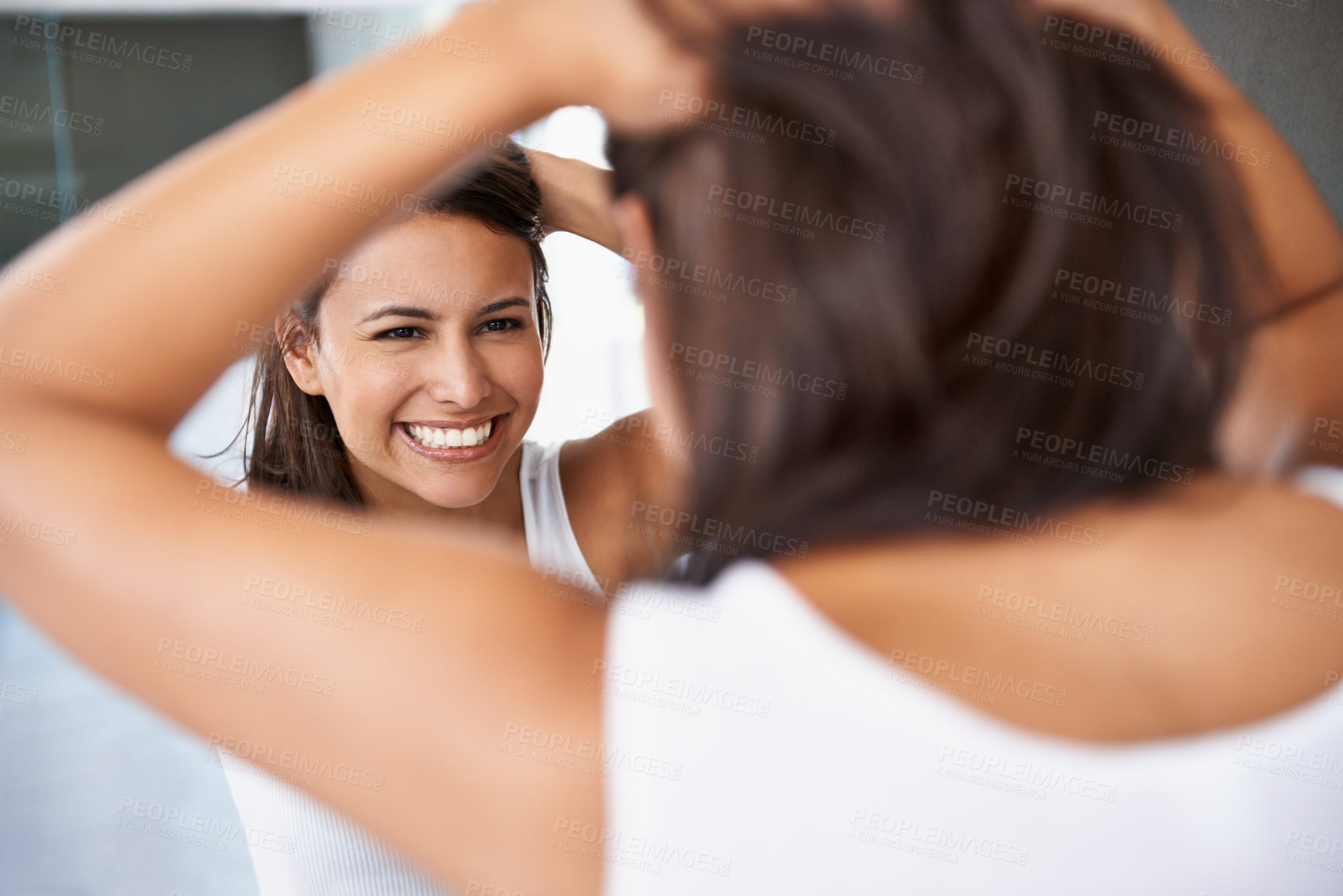 Buy stock photo A cropped shot of a happy young woman deciding on a hair style in front of her bathroom mirror