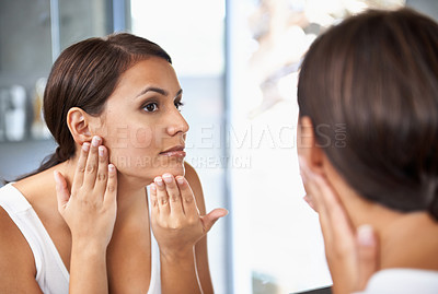 Buy stock photo A beautiful young woman looking at her face in the mirror