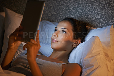 Buy stock photo Beautiful young woman playing on her digital tablet before bed